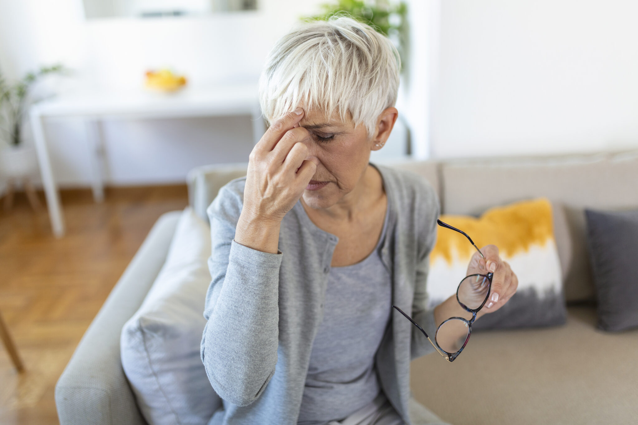 Senior woman in glasses rubs her eyes, suffering from tired eyes, ocular diseases concept